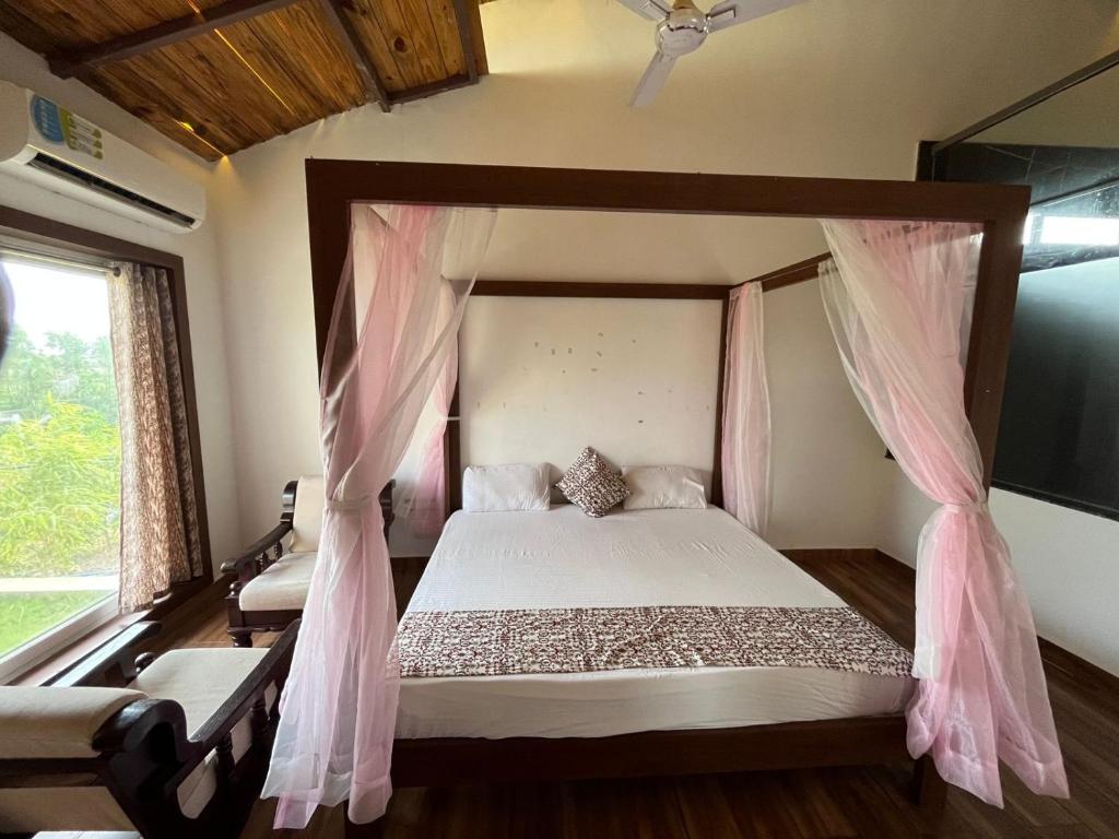 a bedroom with a canopy bed with pink drapes at Unique Resort And Restaurant in Porbandar
