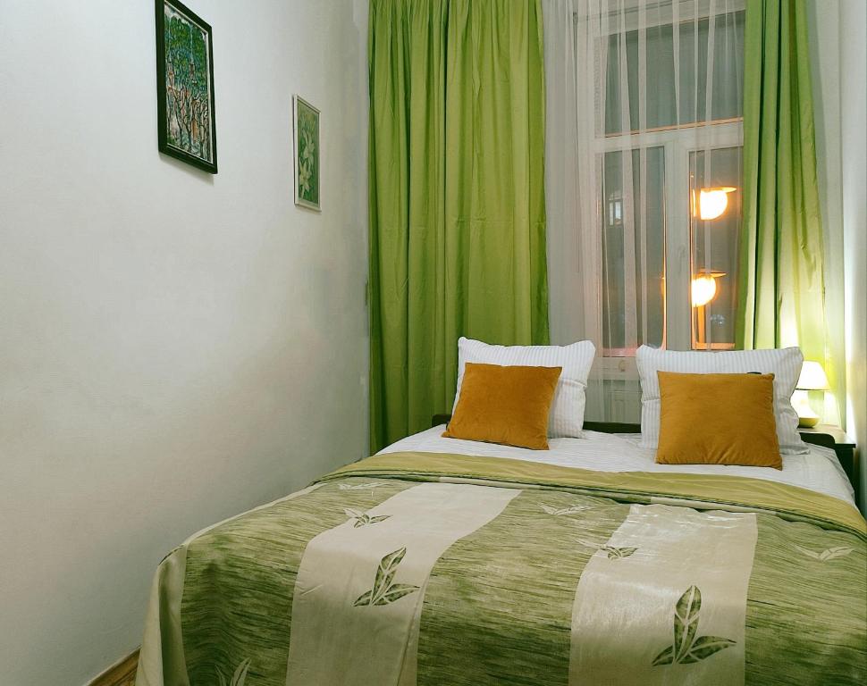 リヴィウにあるАпартаменты на 6х Проспект шевченка центрのベッドルーム1室(緑のカーテンと窓付きのベッド1台付)