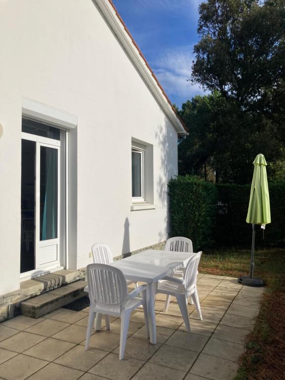 - une table, 2 chaises et un parasol sur la terrasse dans l'établissement Maisonnette au calme prôche forêt et bord de mer, à Saint-Jean-de-Monts