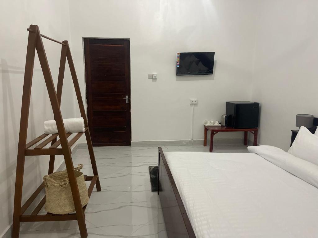 una habitación con una cama y una silla y un televisor en Nashu House Stone Town, en Ngambo