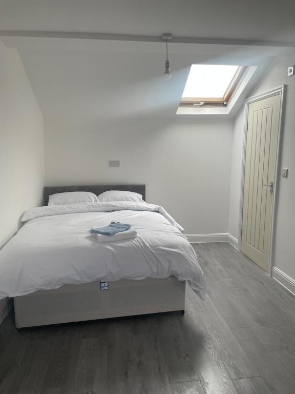 a white bedroom with a bed and a skylight at VicVic Guest house in Oldham