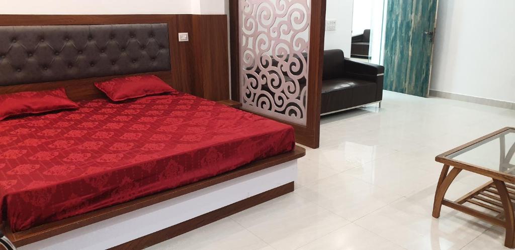 a bedroom with a bed with a red comforter and a chair at Modernio Guest House Noida Extension in Greater Noida