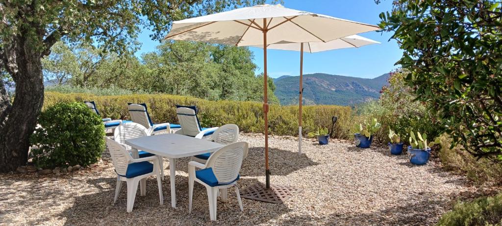 une table et des chaises blanches sous un parasol dans l'établissement Le Bungalow Bleu Domaine des Canebieres Golfe de St Tropez, au Muy