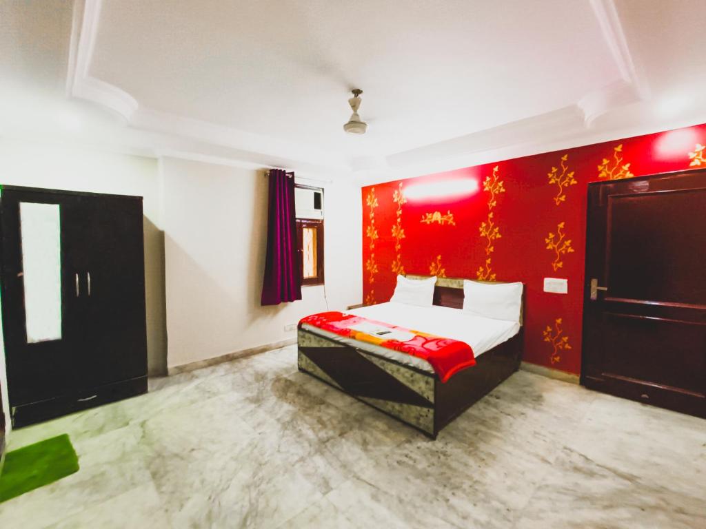 ein Schlafzimmer mit einem Bett und einer roten Wand in der Unterkunft Roomshala 155 Hotel JPC - Malviya Nagar in Neu-Delhi