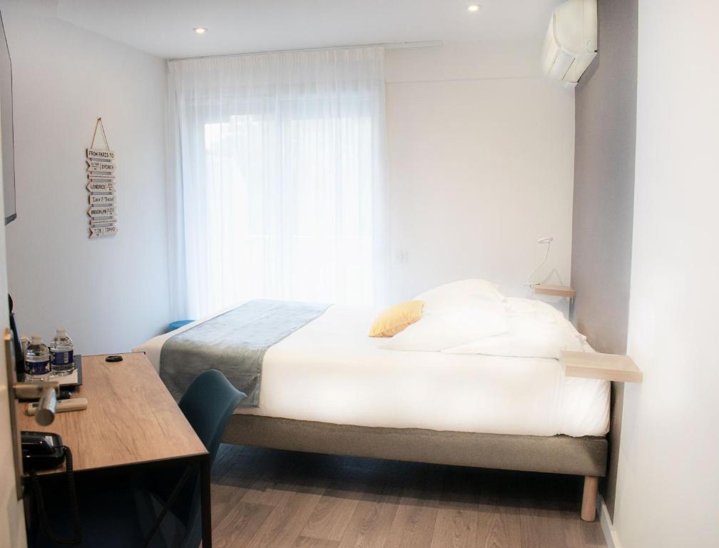 a bedroom with a bed and a desk and a window at Tiercé Hotel in Cagnes-sur-Mer