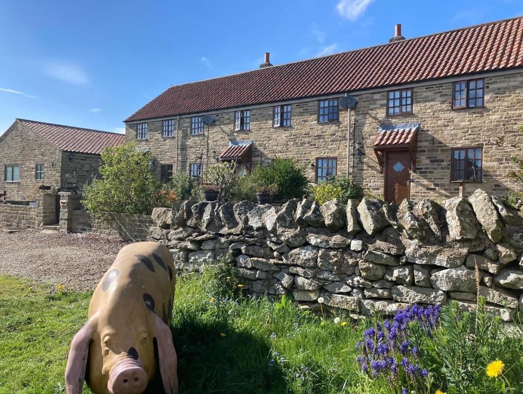 a statue of a pig in front of a stone wall at Charming Farm based cottage with hot tub and sauna in Newton