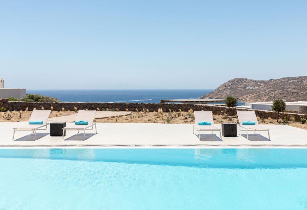 una piscina con sillas y el océano en el fondo en Villa Elia Breeze Mykonos en Mykonos