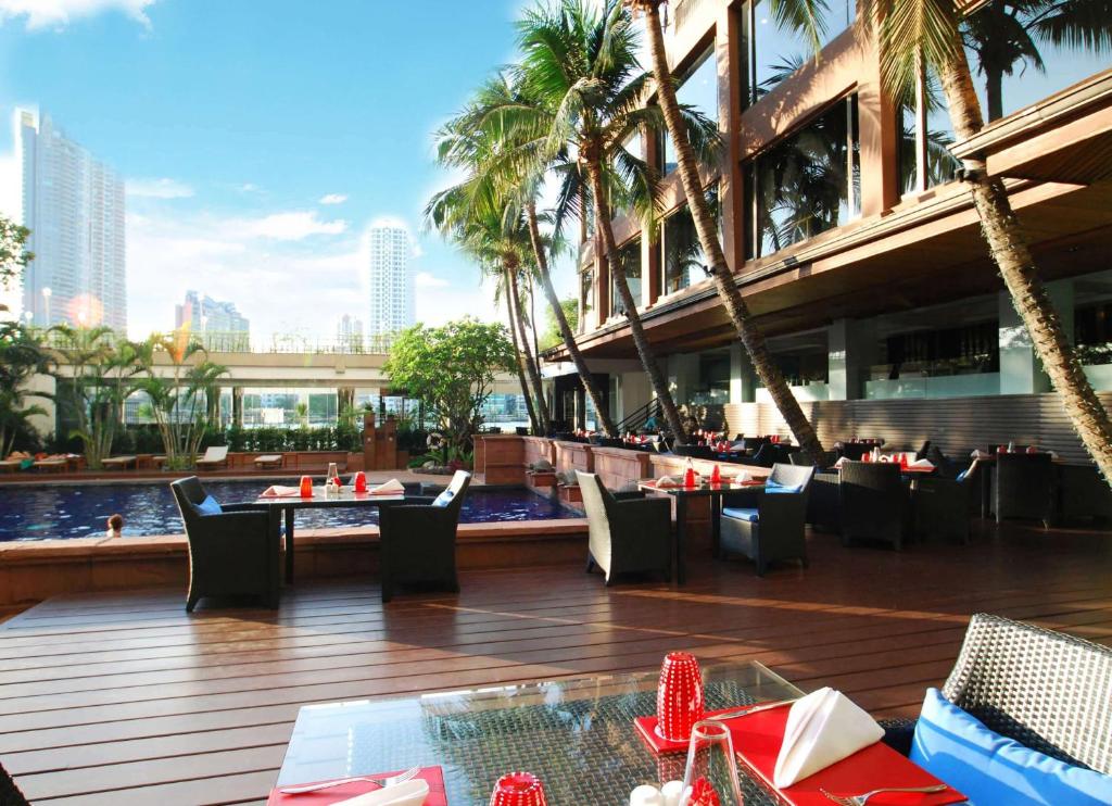 een restaurant met tafels en stoelen voor een gebouw bij Ramada Plaza by Wyndham Bangkok Menam Riverside in Bangkok