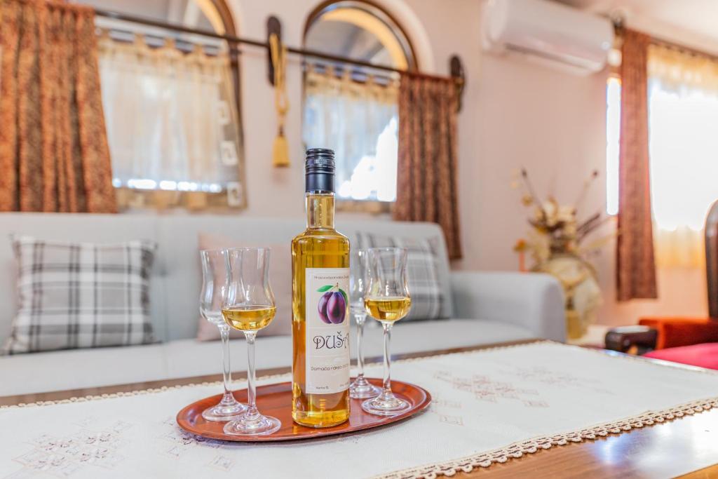 Vikendica Životić في زلاتيبور: زجاجة من النبيذ وكأسين من النبيذ على الطاولة
