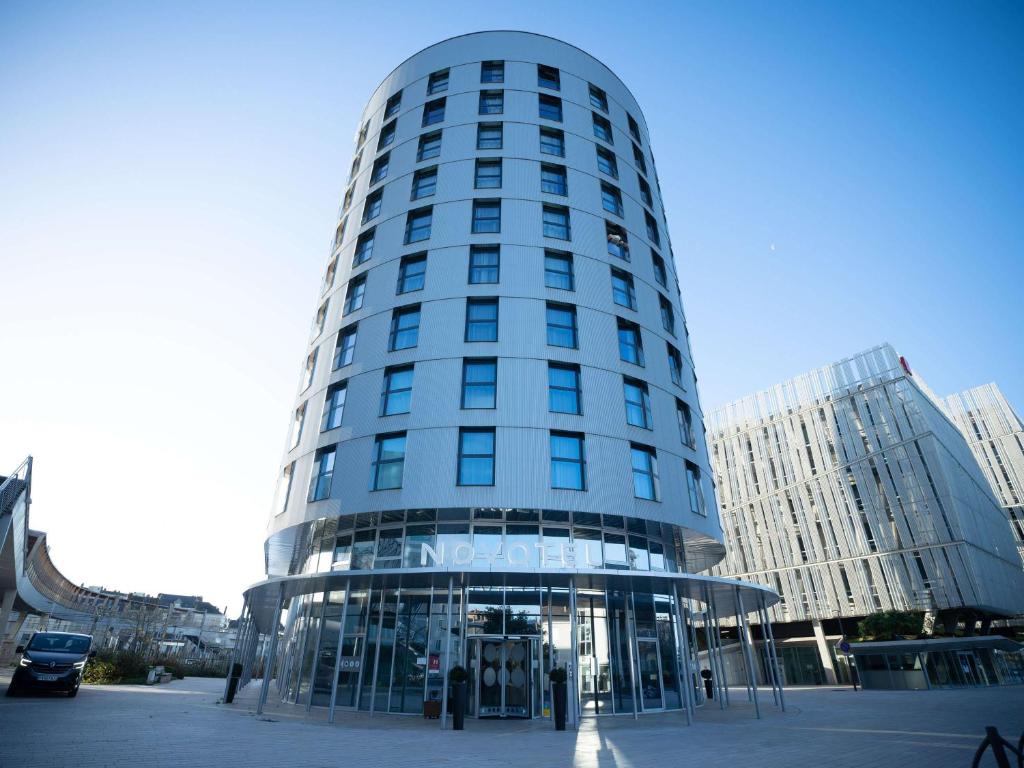 a tall glass building in a city at Novotel Angers Centre Gare in Angers