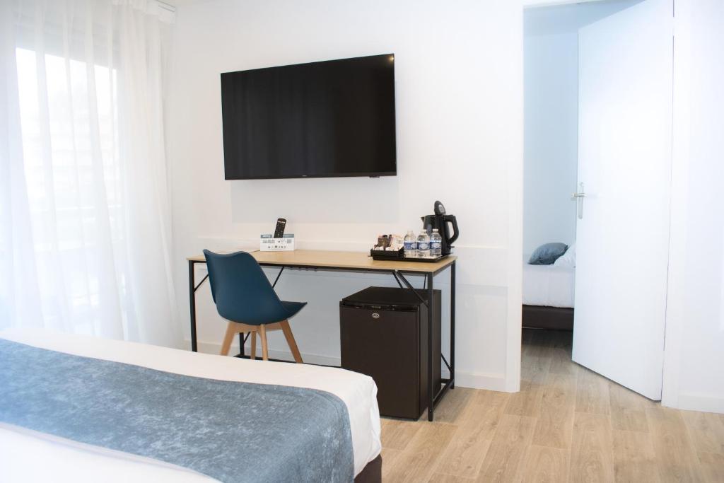 a bedroom with a desk with a tv on the wall at Tiercé Hotel in Cagnes-sur-Mer