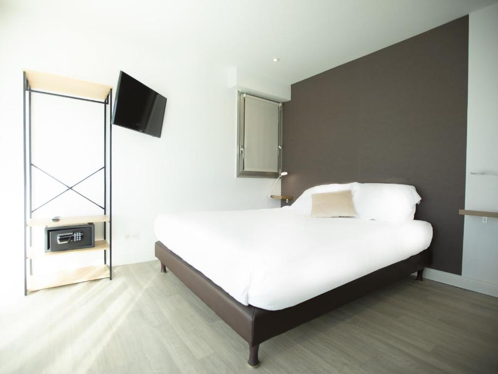 a bedroom with a bed and a tv on the wall at Tiercé Hotel in Cagnes-sur-Mer