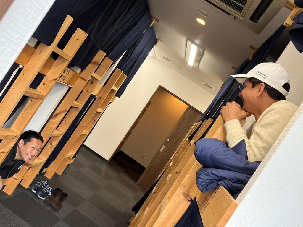 dwóch mężczyzn siedzących w pudełku w budynku w obiekcie 広島ゲストハウス Nice Day w mieście Hiroszima