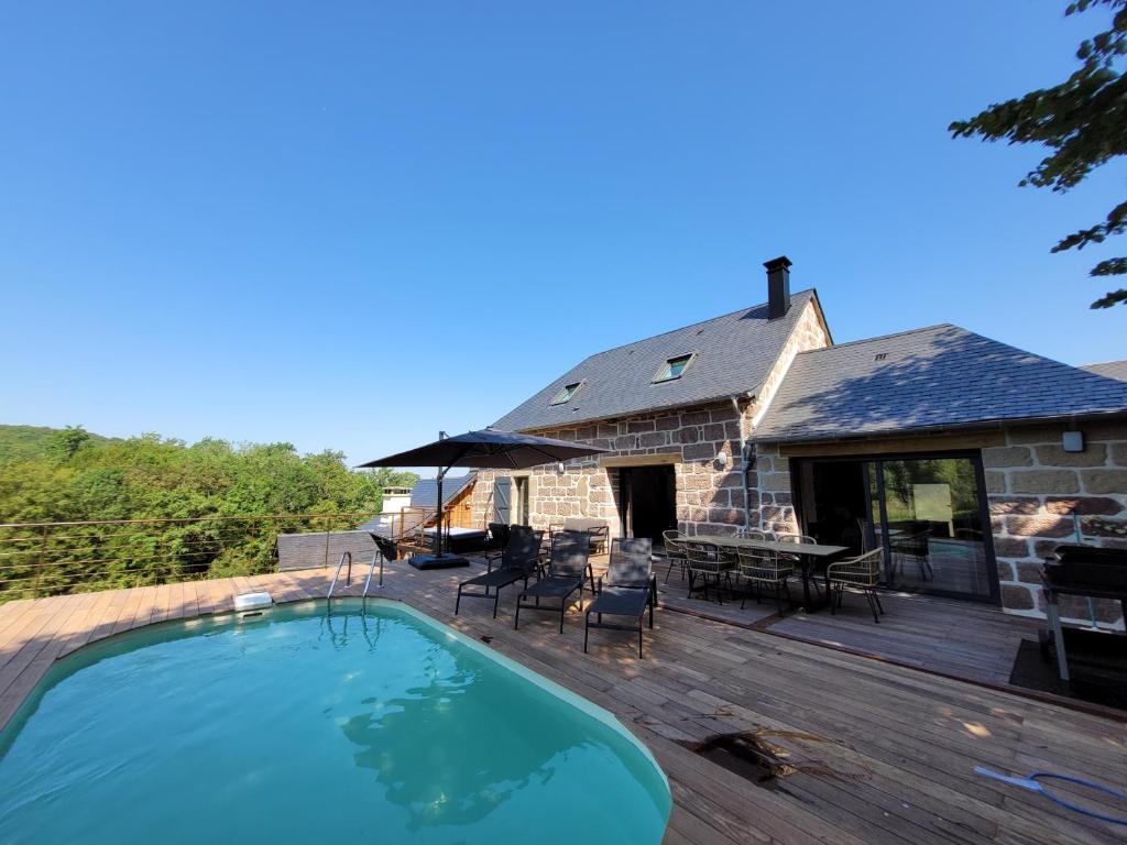 une maison avec une piscine sur une terrasse en bois dans l'établissement Gite de la Quiétude, à Donzenac