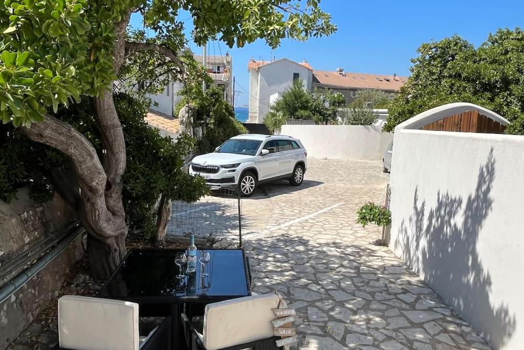 une voiture blanche garée sur un parking avec une table dans l'établissement Maison+terrasse au calme à 100m de l’eau, vue mer, à Marseille