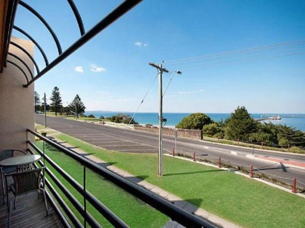 einen Balkon mit Blick auf eine Straße und das Meer in der Unterkunft Accommodation Portland Victoria in Portland