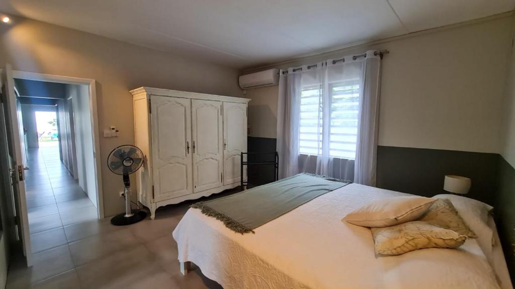 1 dormitorio con 1 cama grande y ventilador en Catch up villa, en Roches Noires