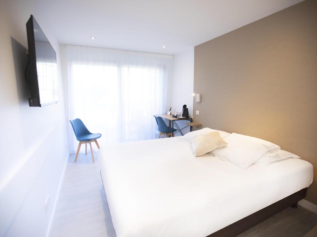 a bedroom with a white bed and a television at Tiercé Hotel in Cagnes-sur-Mer
