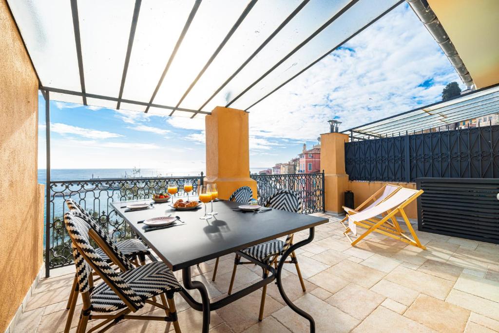 un patio avec une table et des chaises sur un balcon dans l'établissement Le Laurenti, vue mer époustouflante, à Menton