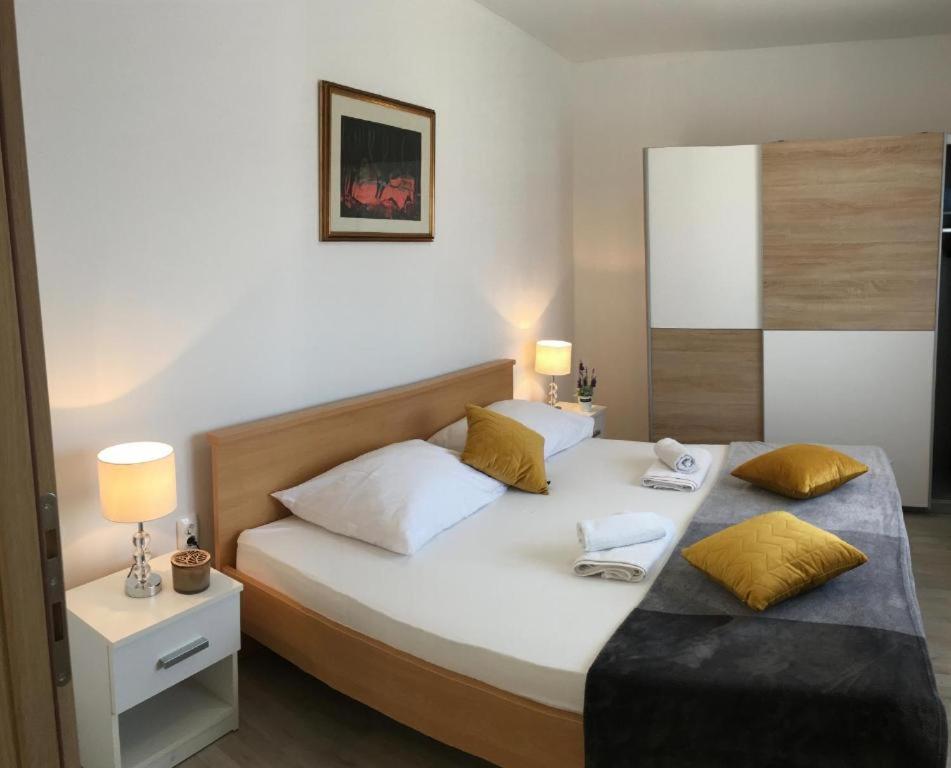 una camera da letto con un grande letto bianco con cuscini gialli di Luxury apartment Cairos a Trogir