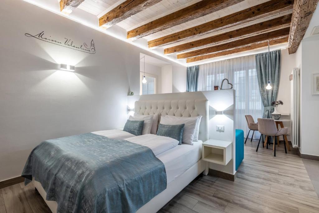 a white bedroom with a large bed and a desk at Maison Valentina in Merano