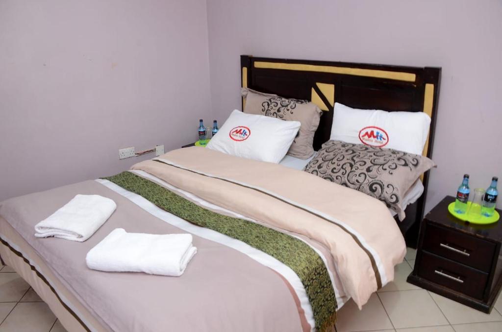 1 dormitorio con 1 cama grande con sábanas y almohadas blancas en Madola Hotel, en Nairobi