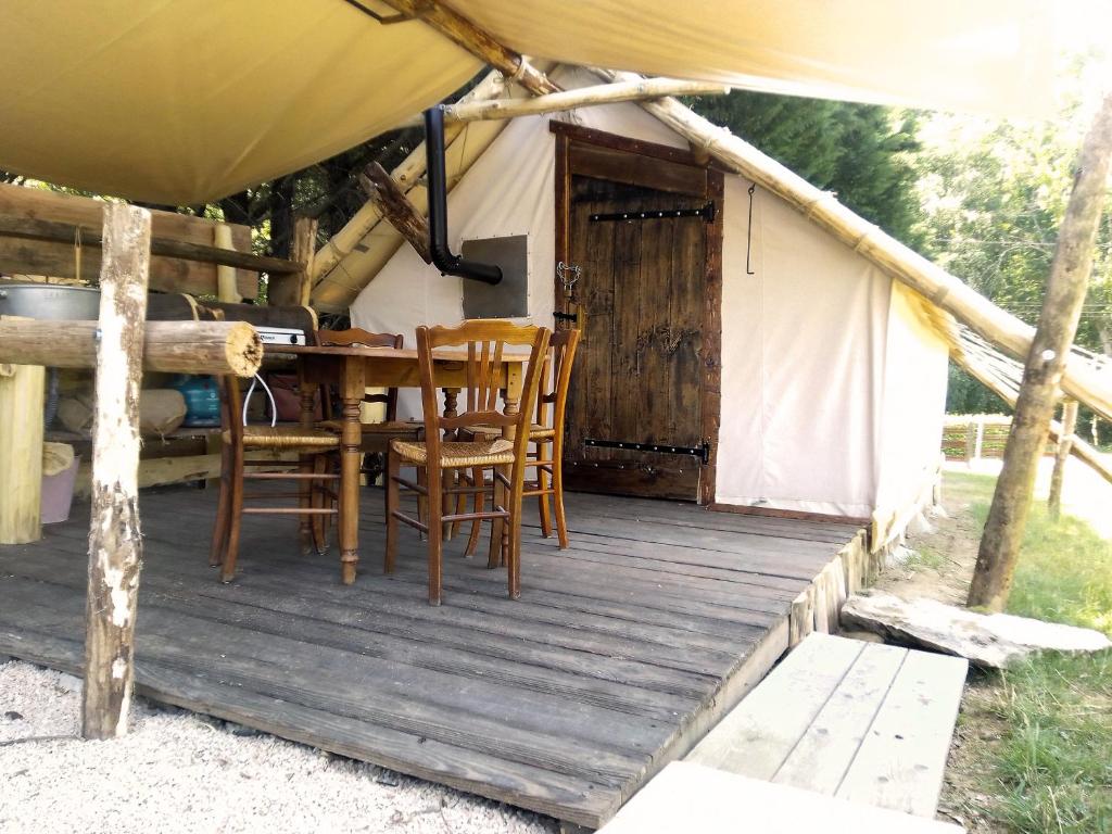 a table and chairs on a porch of a yurt at Tente Trappeur Ada, Au jardin de la Vouivre in Saint-Vincent-en-Bresse