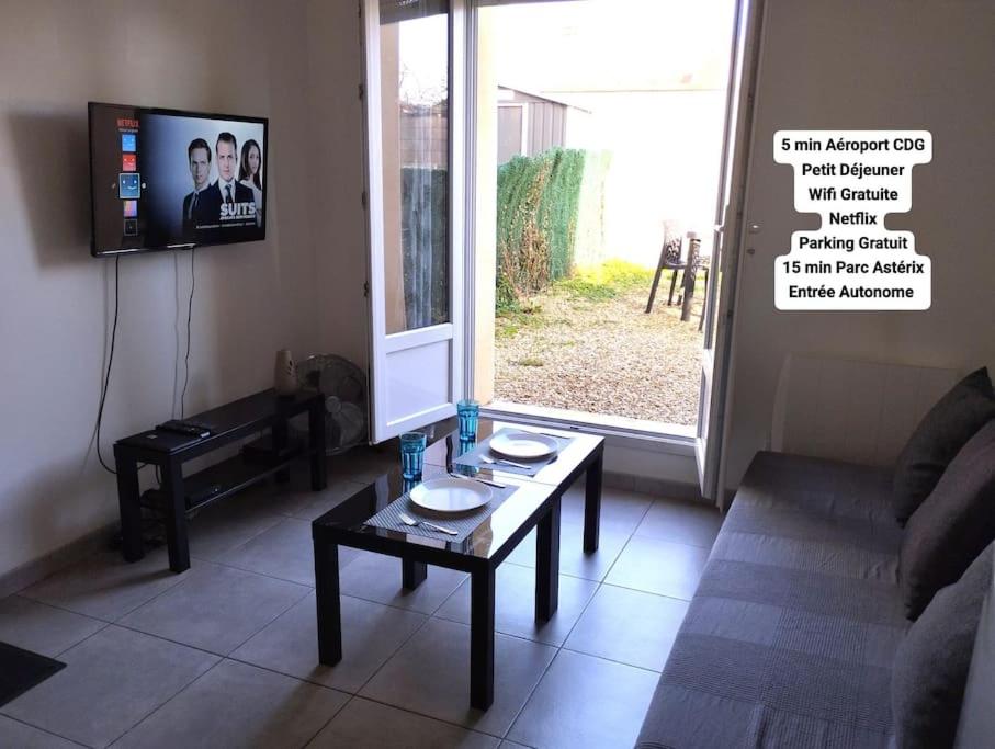 ein Wohnzimmer mit einem Sofa und einem Tisch in der Unterkunft Appartement 2, Jardin, collation, 5 min de l'aéroport CDG in Le Mesnil-Amelot