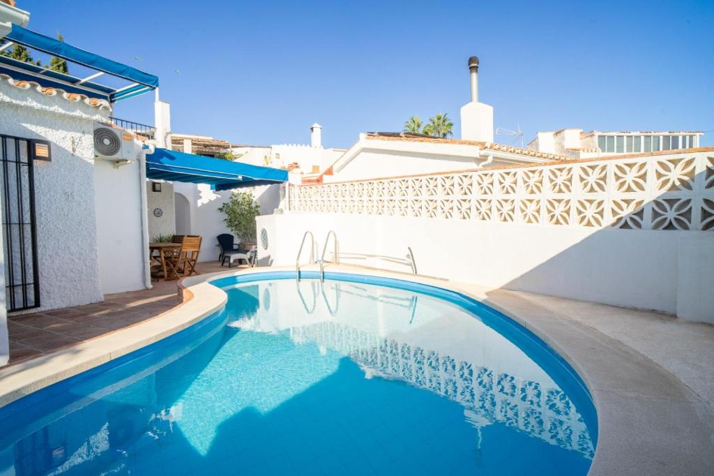 a swimming pool in front of a house with a white wall at Villa Jazmin in Fuengirola