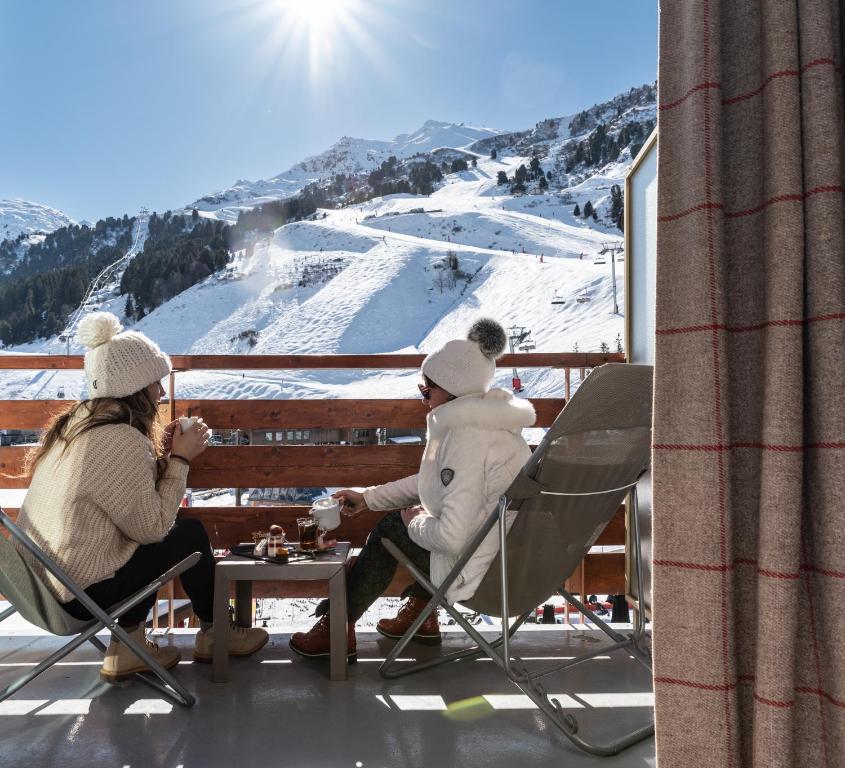 a group of people sitting at a table on a balcony at Hôtel Alpen Ruitor in Méribel