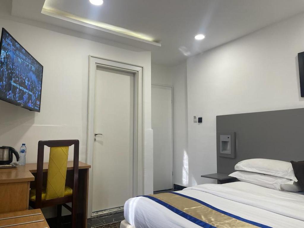 a bedroom with a bed and a desk and a window at Hotel 5092 in Abuja