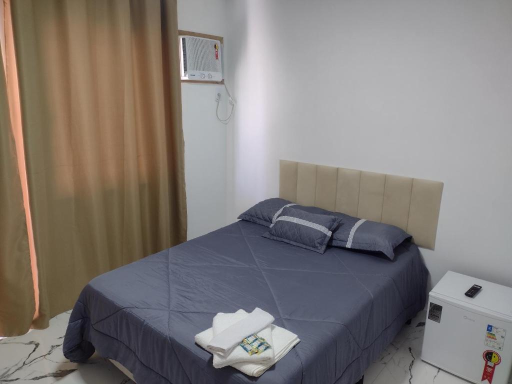 sypialnia z łóżkiem z niebieską pościelą i niebieskimi poduszkami w obiekcie top Suites w mieście Saquarema