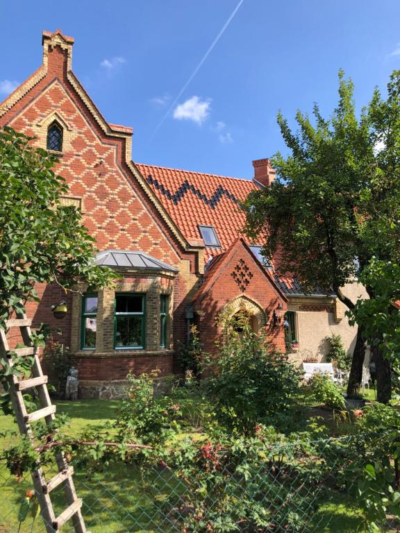 ein großes Backsteinhaus mit einem Zaun davor in der Unterkunft Little Cottage auf 2 Etagen in Raben Steinfeld