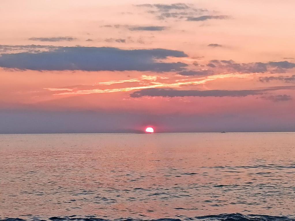 una puesta de sol sobre el océano con el sol en el horizonte en La casa di Lucy, en Torre Ovo