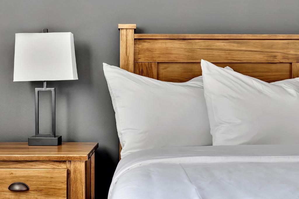 a bed with white sheets and a lamp on a nightstand at The Inn of Lake George in Lake George