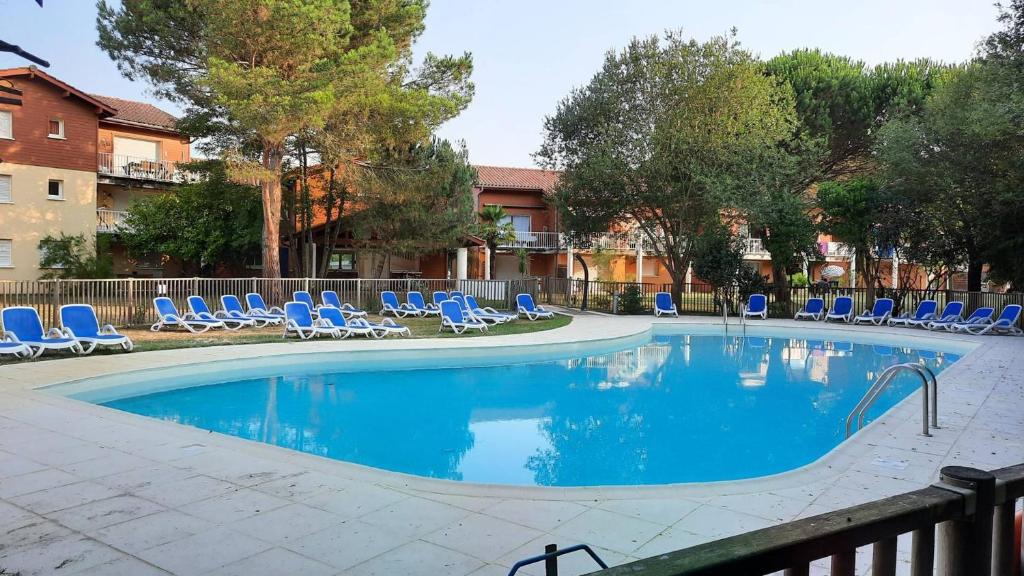 une grande piscine avec des chaises et des chaises bleues dans l'établissement Residence AMARINE Appartement avec terrasse et piscine collective chauffée, à Capbreton