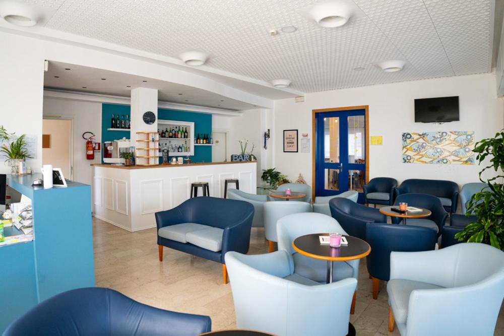 een wachtkamer met blauwe stoelen en tafels bij Hotel Eugenio in Cesenatico