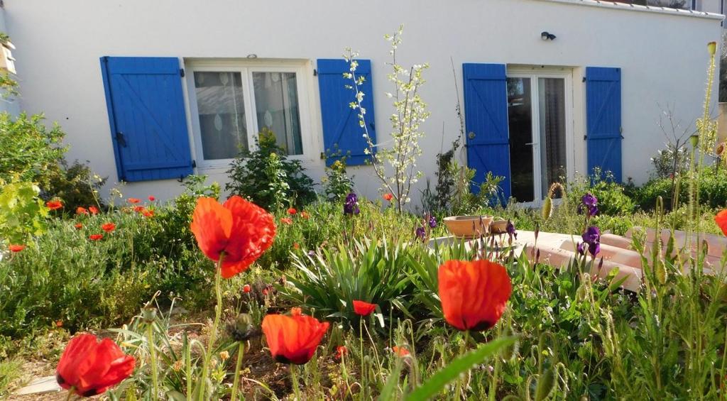 a garden with red flowers in front of a house at Maisonnette de Jardin in Marseille