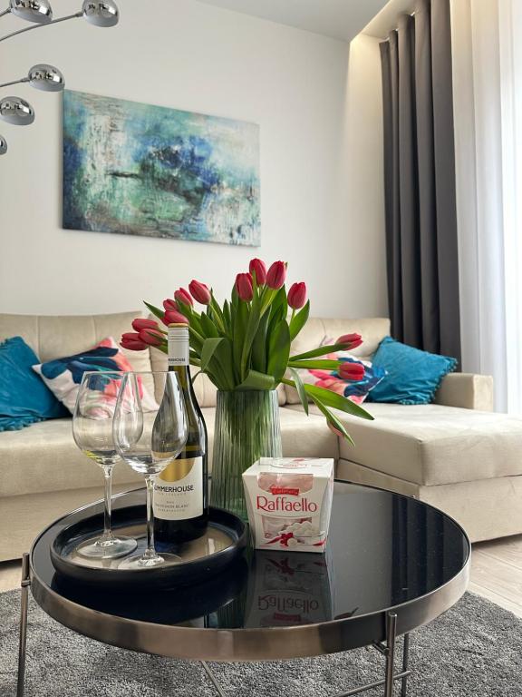 ein Wohnzimmer mit einem Tisch mit Weingläsern und Blumen in der Unterkunft White Apartament Częstochowa Centrum 2-bedroom in Częstochowa