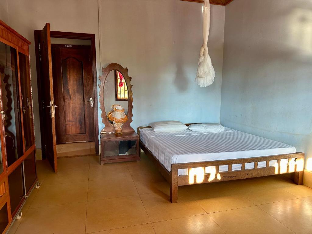 1 dormitorio con cama y espejo en Green Hill Homestay, Restaurant & Treķking en Banlung