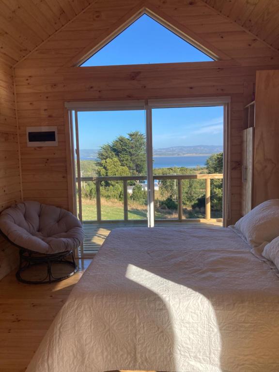 ein Schlafzimmer mit einem Bett und einem großen Fenster in der Unterkunft Lodge Güitimó in Ancud