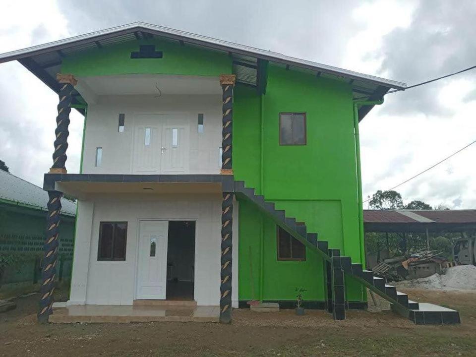 a green and white house with a staircase at Kapowlito Real Estate Casa Grootblijdenshoopweg in Paramaribo