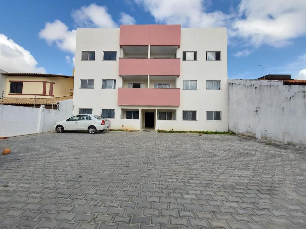 Un bâtiment blanc avec une voiture garée devant. dans l'établissement Residencial Atalaia Sul, à Aracaju