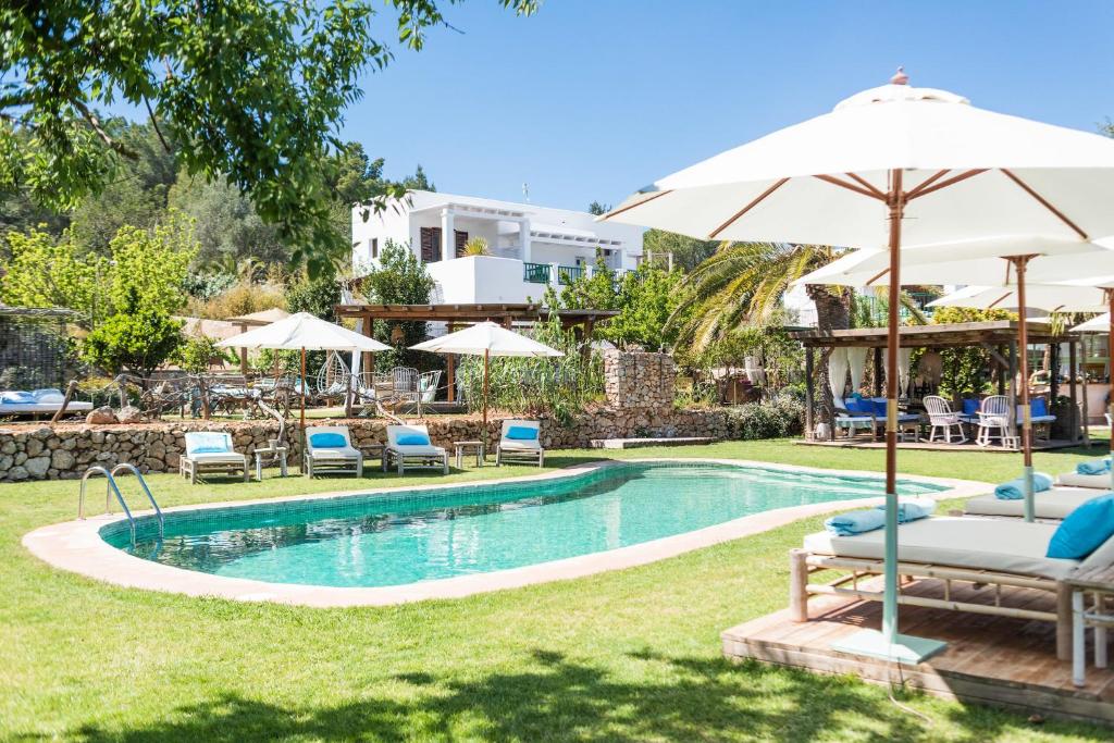 a swimming pool with chairs and umbrellas in a yard at ES CUCONS RURAL HOTEL in San Antonio