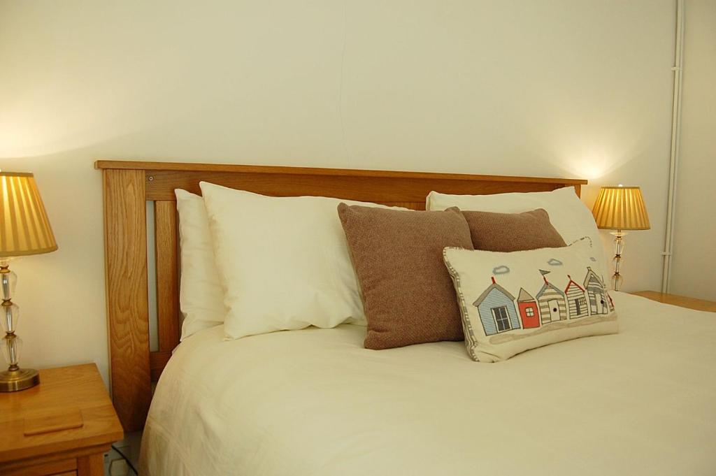 a bed with white sheets and pillows and two lamps at Ty Traeth Beach House in Tywyn