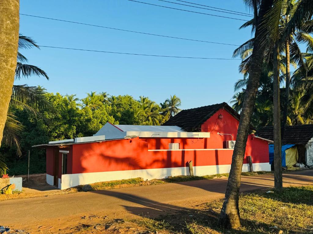 um edifício vermelho ao lado de uma rua com palmeiras em Payal Nivas beach cottage em Padubidri
