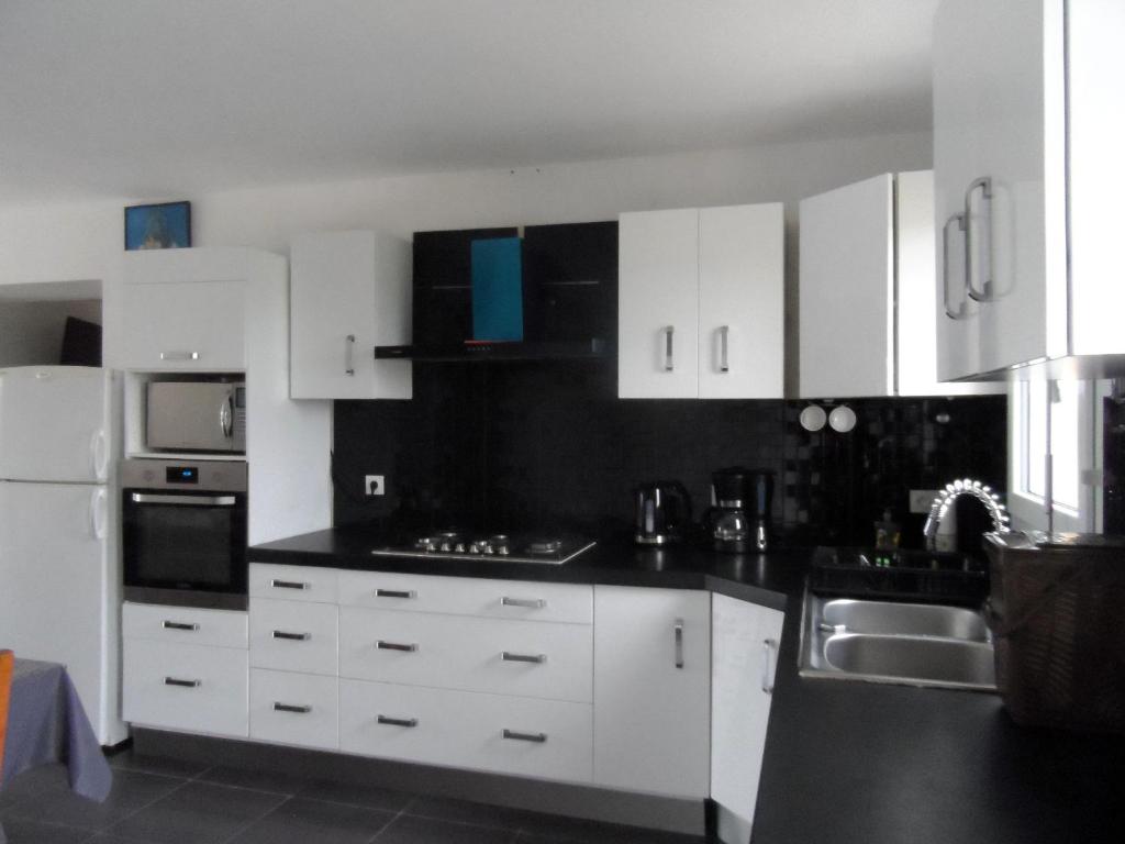 a kitchen with white cabinets and black counter tops at La casa en el campo A 20 minutes de Zoo Beauval &amp; 8 minutes de la flamme olympique à Valençay in Vicq-sur-Nahon