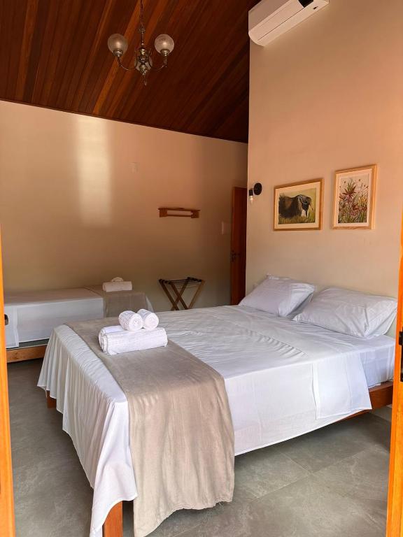 a bedroom with two beds with white sheets and towels at Pousada Mãe Natureza in Pirenópolis
