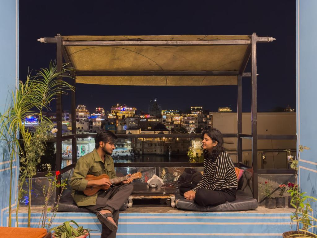a man and woman sitting on the ledge of a building at Madpackers Udaipur in Udaipur