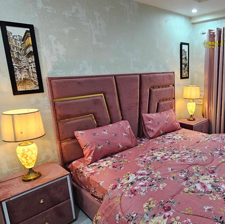 a bedroom with a bed with pink sheets and lamps at 1 Bed Luxury Apartment in Lahore